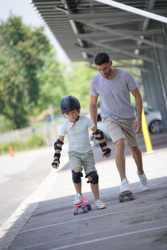 Young boy with dad learning how to skate