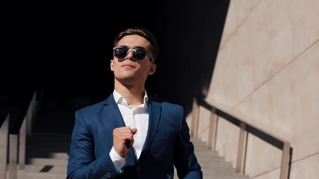 Young happy businessman celebrating and funny dancing directly into the camera celebrating his achievement and success. Slow motion