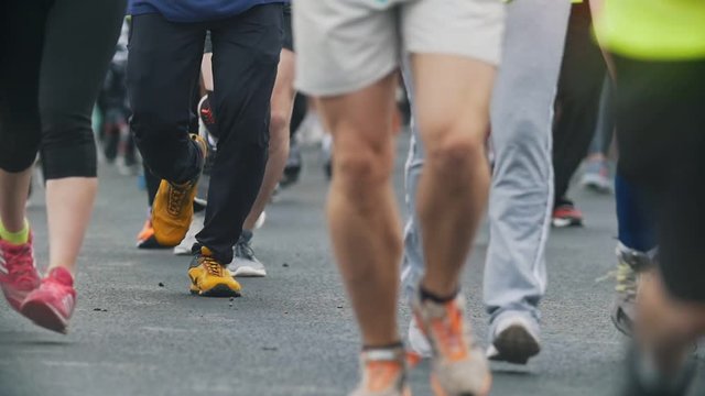 Jogging - legs sportsmen runners at the marathon in the city, slow-motion