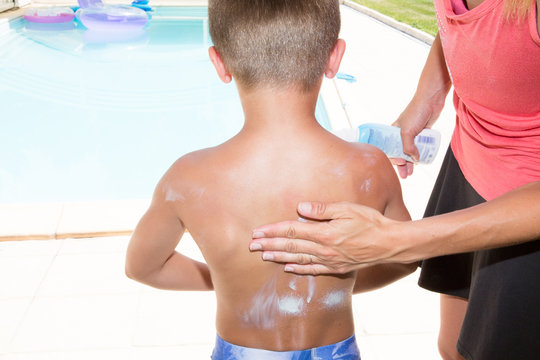 Suncare On The Swimming Pool Mother Applying Sunscreen On Child Son Boy Back