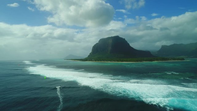 Following and tracking kitesurfer with drone in Le Morne, Mauritius, beautiful summer's day with perfect waves, beautiful scenery. Aerial view in paradise.