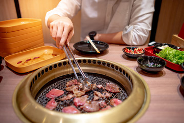 Young Asian man eating Korean Barbecue buffet grilling beef in the restaurant