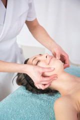 Obraz na płótnie Canvas Face lifting and body face massage to beautiful girl in cosmetology cabinet or beauty spa parlor