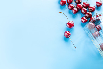 Naklejka na ściany i meble Sweet cherry ripe in a glass Cup scattered on a blue background, summer, fruit, healthy food. Flat lay and copy space.