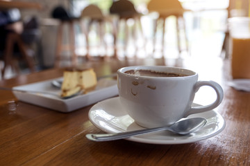 A cup of coffee and a piece of cake on table in cafe