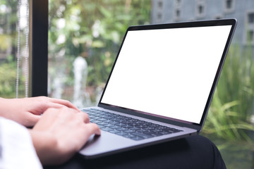 Mockup image of woman's hands using and typing on laptop with blank white desktop screen while sitting in cafe