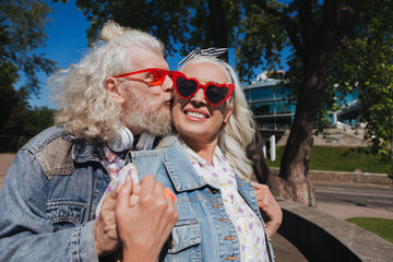 Real feelings. Delighted bearded man kissing his wife while showing his feelings to her