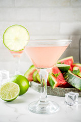 Alcoholic summer beverage, watermelon martini cocktail, with fresh lime and mint, white marble background copy space
