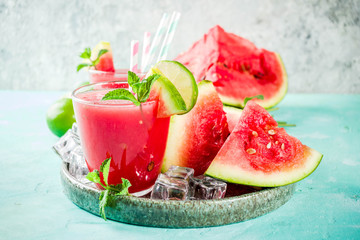 Fruity summer cold drink, homemade watermelon juice or smoothie served with lime and fresh mint leaves, light blue trendy background copy space