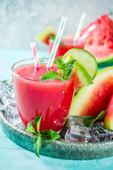 Fruity summer cold drink, homemade watermelon juice or smoothie served with lime and fresh mint leaves, light blue trendy background copy space top view