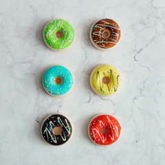 Creative arrangement of colorful donuts on marble background. Minimal food concept. Flat lay.