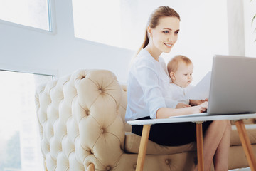 Working atmosphere. Pleased young woman keeping smile on her face while looking at screen of her...