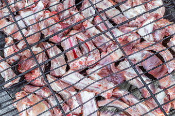 Raw pork ribs on cast iron grill . People Making barbecue and having lunch in the nature at summer.