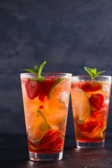 Strawberry mojito cocktail with berries, lime and mint. Summer berry cocktail on black background. space for text, vertical