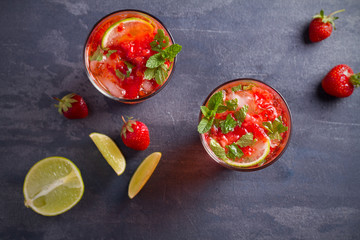 Strawberry mojito cocktail with berries, lime and mint. Summer berry cocktail on black background. overhead, horizontal