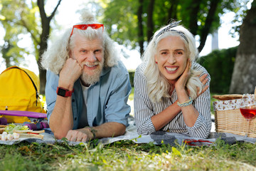 Our picnic. Pleasant joyful couple lying on the grass while having a picnic together