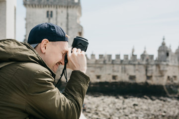 A professional photographer or a young male tourist photographes the sights in Lisbon in Portugal. Leans the camera to his head and laughs. Very satisfied with the photo