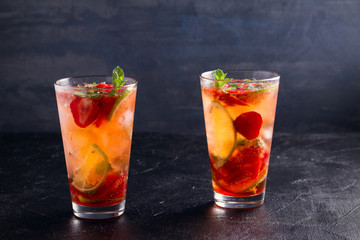 Strawberry mojito cocktail with berries, lime and mint. Summer berry cocktail on black background. space for text, horizontal