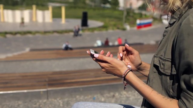 close-up of a girl holding a phone while sitting in the park
