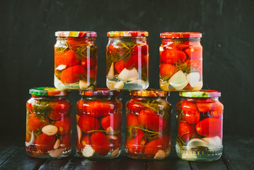 Several jars of canned tomatoes with ripe tomatoes and garlic