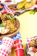 Different fruits and vegetables are cooked on the grill. Yellow background. Summer dinner. . Copy space,