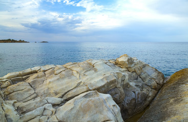 Rocks on the shore of sea and the city of Hersonissos, Crete, Greece.