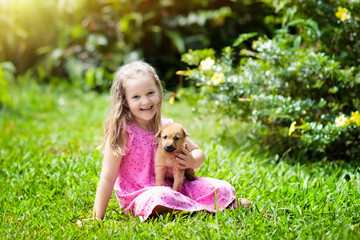 Kids play with puppy. Children and dog in garden.