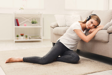 Young sad woman in headphones on floor