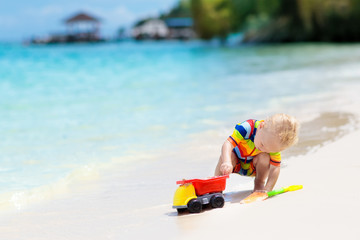 Kids play on tropical beach. Sand and water toy.