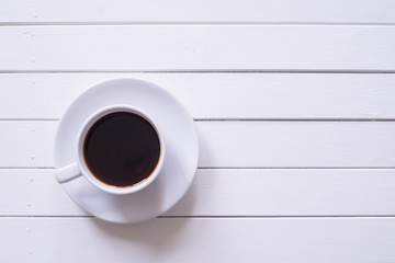 A cup of black coffee on rustic white wooden table with copy space.