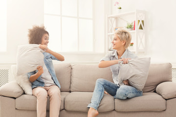 Two young women having pillow fight on sofa