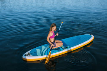 Fototapeta na wymiar view from above shot of woman sitting on paddle board at sea