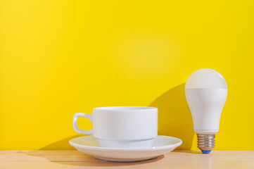 Bulb,notebook,Alarm clock and a cup of coffee on wooden table over yellow background.Fresh idea,idea development,good idea and list of idea concept.