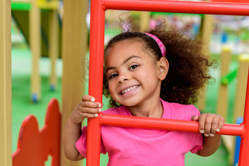 smiling curly african american little child climbing on stairs at playground