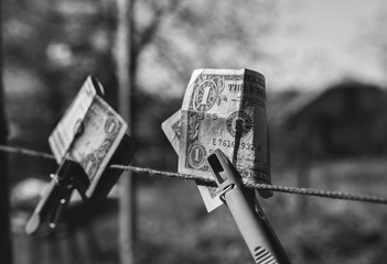 Dollars hanging on the clothes pegs outdoors. Money drying on clothes pin in the green yard on sunny day. Poverty economic situation photo.