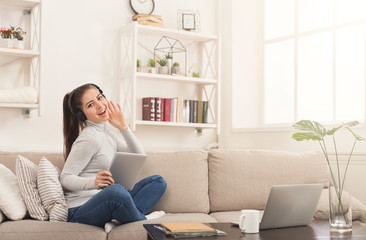 Happy young woman in headphones on beige couch