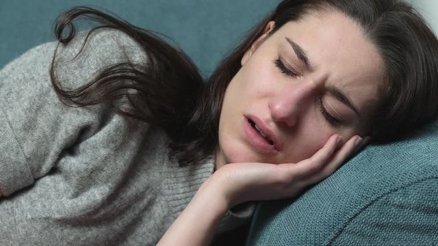 Lonely depressed youn woman crying lying on the couch