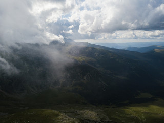 Aerial view over mountain top. Summer clouds and fog in the background