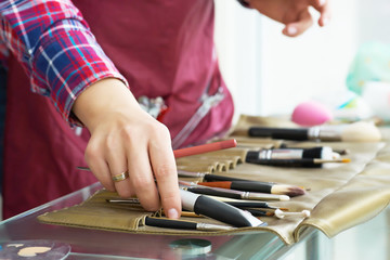 Close-up image of make-up artist hand choosing brush from the set.