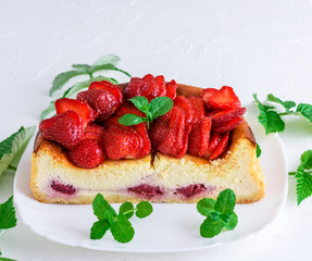 half cheesecake with strawberry berries on a white ceramic plate