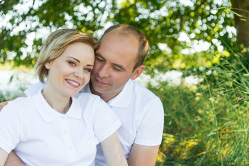Fototapeta premium ouple in love. Man and woman in an embrace. A couple sitting in the grass in white T-shirts.