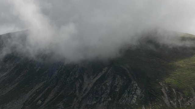 Spectacular fast mouving clouds up in the mountains. Dramatic clouds covering peak of the mountains
