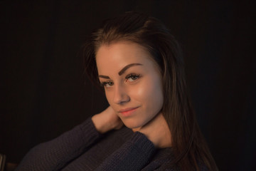 Naklejka premium Beautiful young girl wearing sweater posing on black studio background touching her head with hand