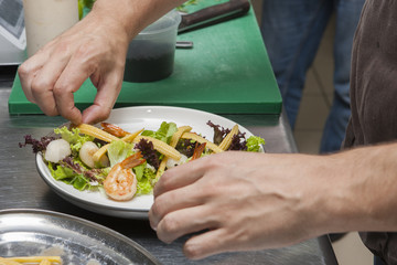 Obraz na płótnie Canvas The cook prepares a seafood salad Hands of the cook