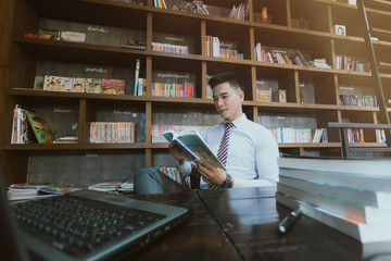 Young businessman sitting at a coffee shop.  Young business man reading a book.