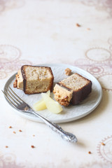 Two Pieces of Almond Pear Loaf Cake covered with Chocolate Glaze, topped with Caramel Cream Cheese Frosting and decorated with Spicy Crumble, on light beige background. 