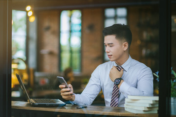 Young businessman sitting at a coffee shop.  Young business man reading a book.