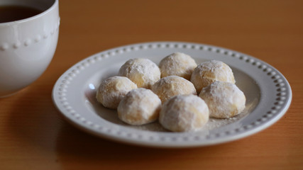 Snow White Cookies or Puteri Salju and a cup of tea with wood background.