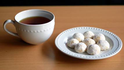 Snow White Cookies or Puteri Salju and a cup of tea with wood background.