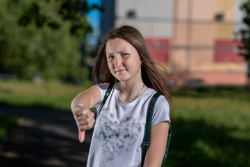 Teenage girl schoolgirl. Summer in nature. The gesture of the Hand shows the finger down. Concept...